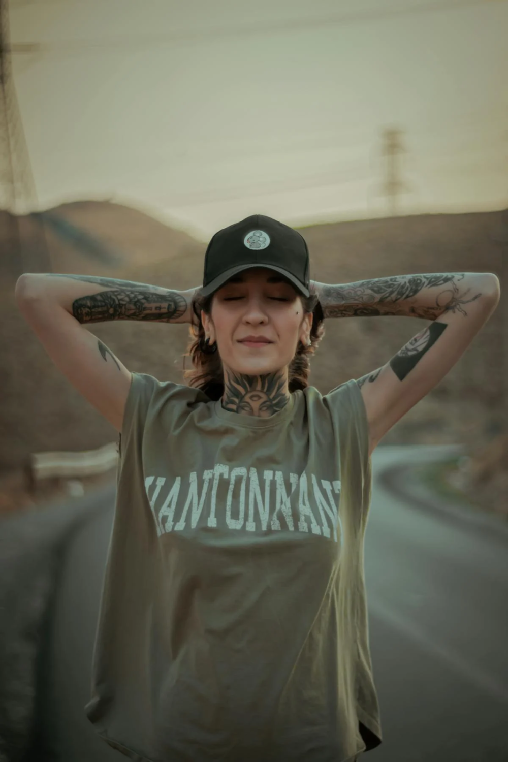 a woman with tattooed arms relaxing while standing straight and closing her eyes