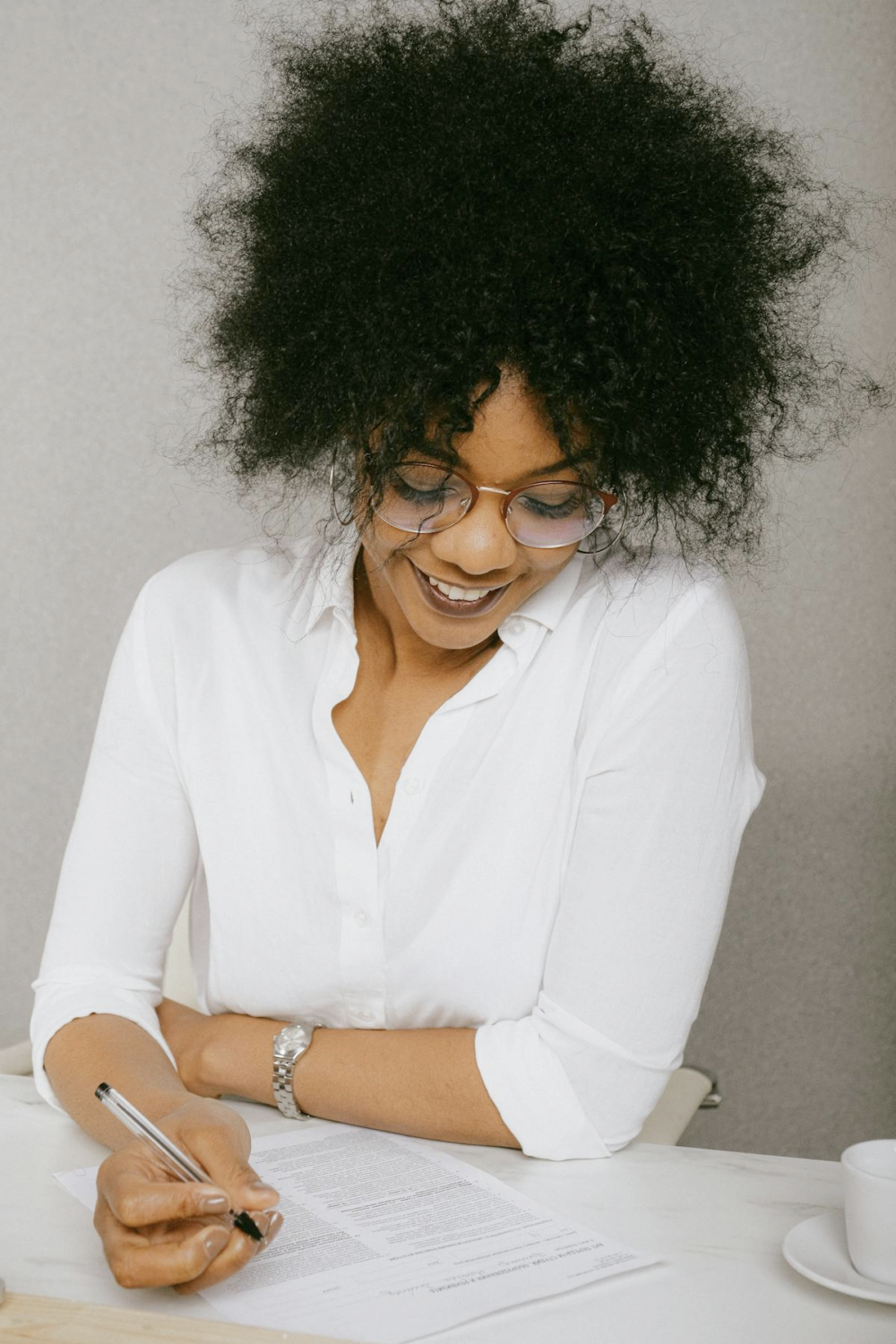a smiling woman with curly frizzy hair smiling and writing something