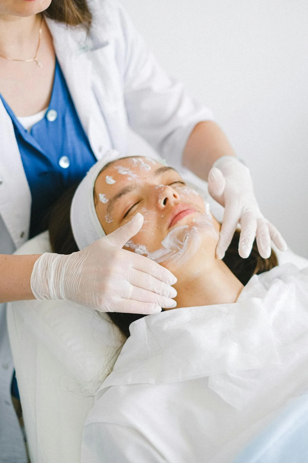 a woman at a skin care session where someone is applying lotion on her face