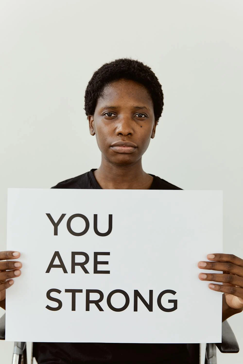 a woman holding a placard stating "you are strong"