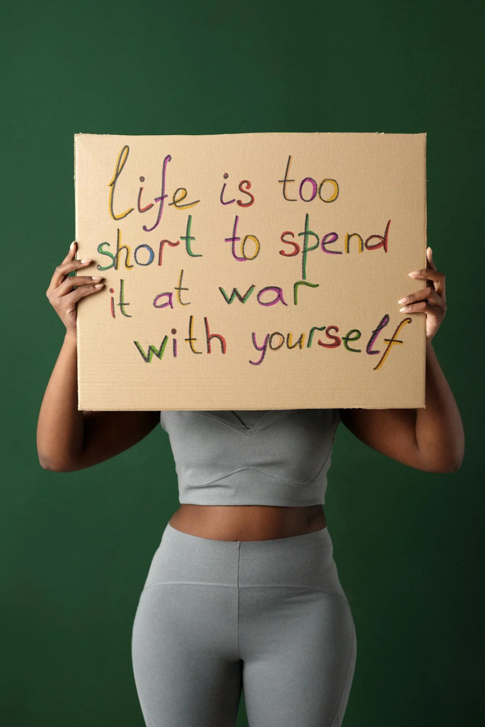 a woman holding a placard stating "life is too short to spend it at war with yourself"