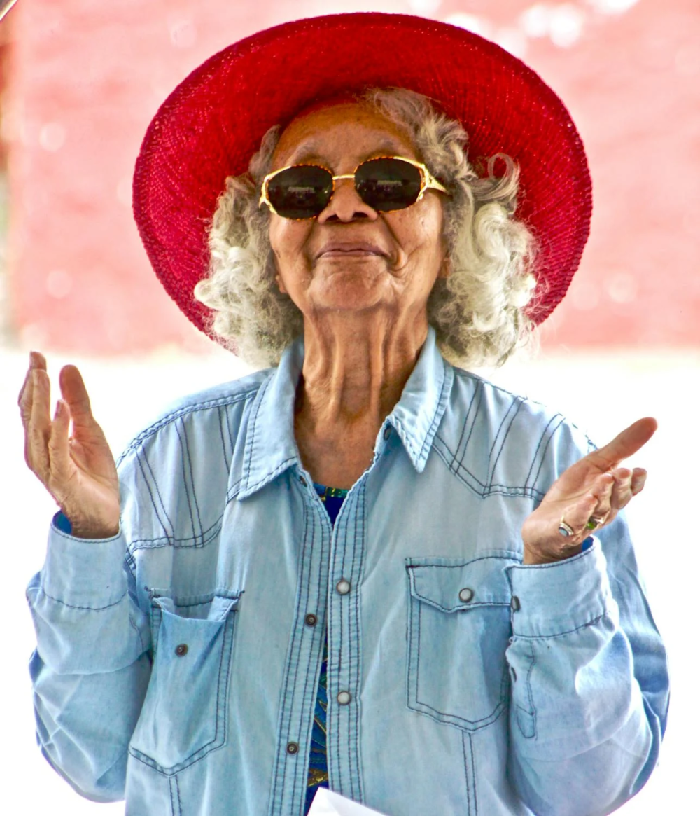 portrait shot of an old woman with grey hair wearing a red hat